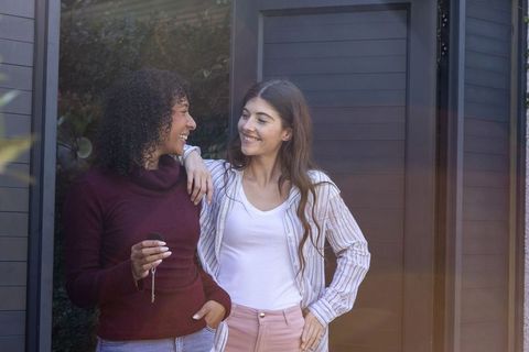 Diverse Female Friends Standing at Modern Home Entrance Holding Keys