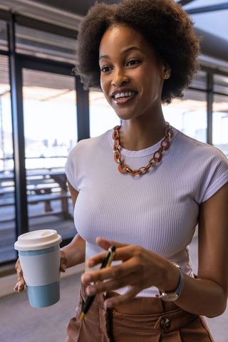 Urban businesswoman with travel mug at workplace