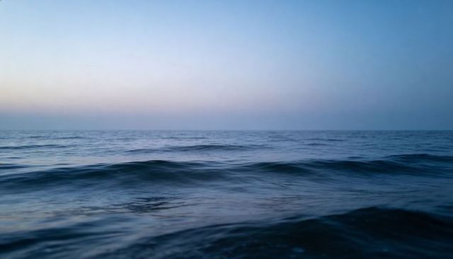 Calm ocean surface at dawn with soft gradient sky and gentle rolling waves minimalist