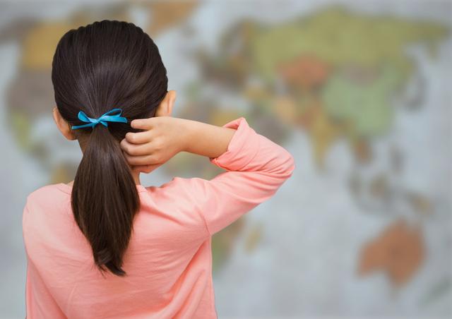 Young girl standing with her back to the camera, wearing a blue ribbon in her hair, looking at a blurry world. Ideal for concepts related to global learning, childhood curiosity, education, and travel. Suitable for educational materials, international travel promotions, and geography learning tools.
