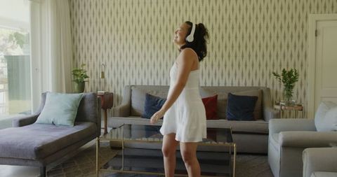 Joyful woman dancing at home listening to music with wireless headphones