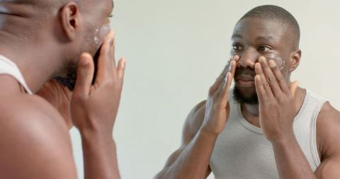 Man applying skincare product facing mirror for fresh grooming routine