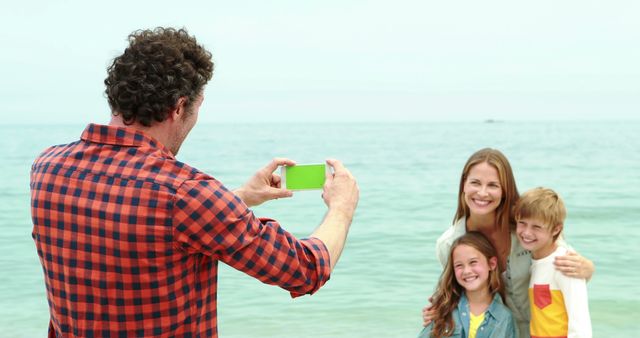 Father taking photo of smiling family at beach - Download Free Stock Images Pikwizard.com