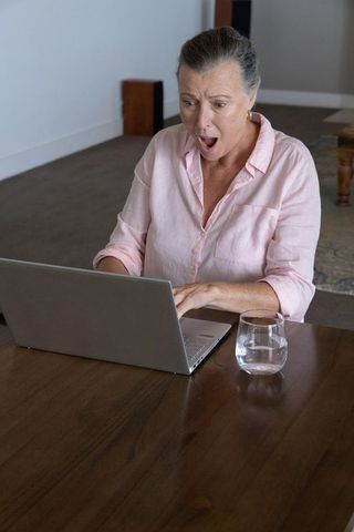 Surprised woman working at home on laptop
