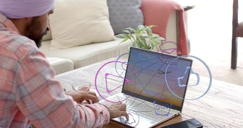 Man wearing turban working remotely on laptop at home with social media icons and smartphone