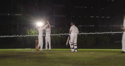 Night cricket celebration under floodlights with batsman and fielders, digital data overlay