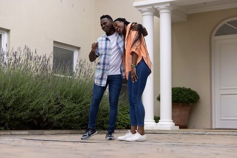 African American Couple Standing and Leaning on Suburban Porch Beside Lavender and Columns