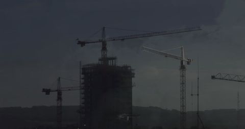 Construction Cranes Against Dark Sky Over High-Rise Building - Download Free Stock Images Pikwizard.com