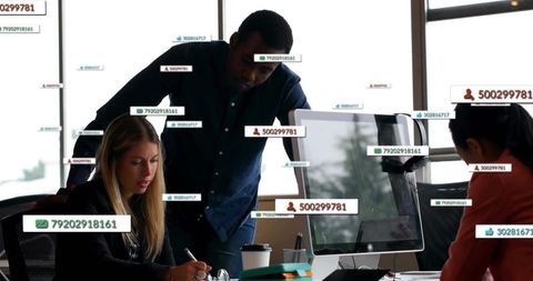 Team collaborating around desktop with floating data labels and modern office workspace