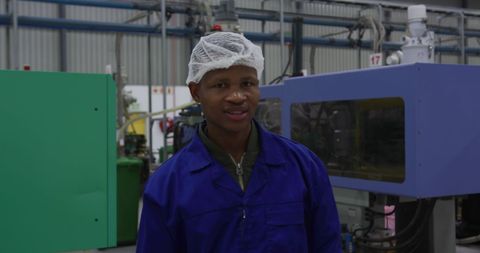 Smiling Factory Worker in Protective Gear in Industrial Warehouse