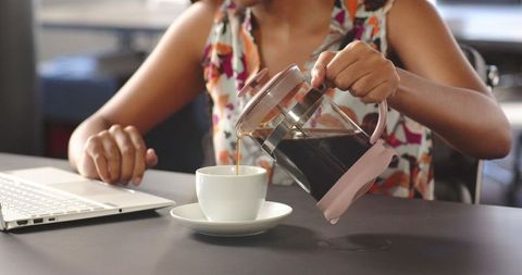 Entrepreneur Poruing Coffee While Working at Laptop in Modern Office