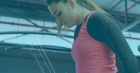 Focused Female Athlete Analyzing Workout Data in Modern Gym