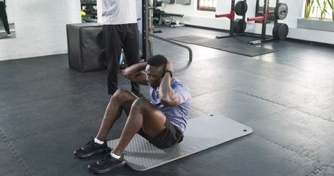 Personal trainer guiding sit-ups in modern gym