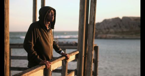 Young African American Jogger Relaxing on Sunny Beach Pier