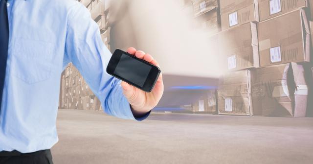 Digital composite of Businessman showing smart phone with blank screen in warehouse