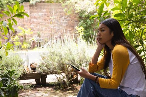 Woman Relaxing with Smartphone in Serene Garden Environment