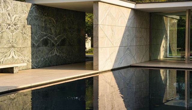 Minimalist marble pavilion reflecting in dark reflective pool at modern glass courtyard oasis