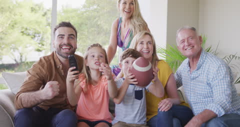 Multigenerational Family Cheering While Watching TV at Home