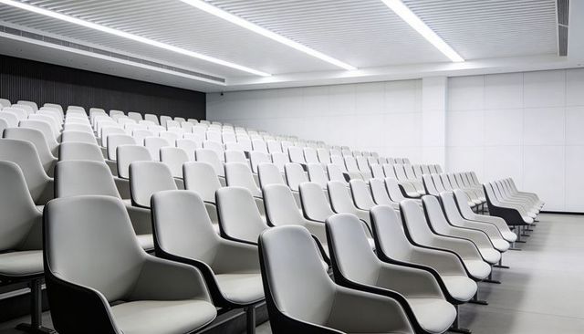 Modern Empty Lecture Hall Featuring Tiered White Molded Seats and Linear Ceiling Lights