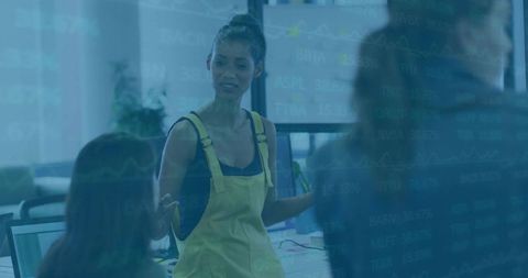 Female Team Leader Explaining Project in Open Office with Screens and Stock Charts