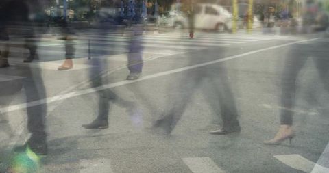 Motion-blur commuters walking across urban crosswalk with heels, boots and sneakers