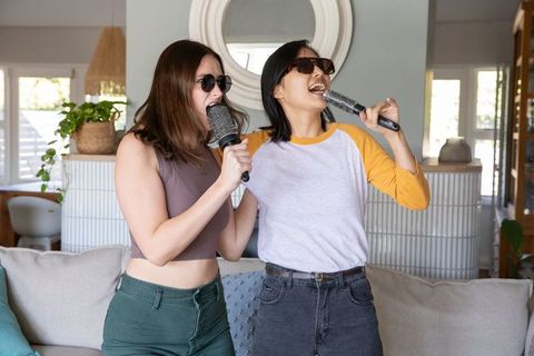 Diverse friends singing karaoke in living room