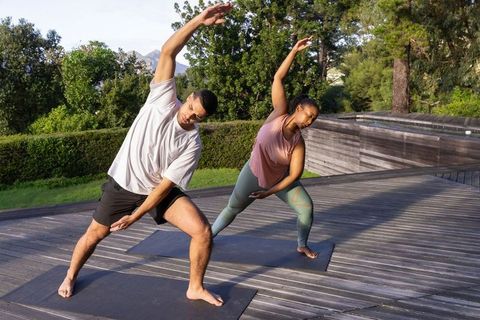 Diverse Couple Practicing Yoga Outdoor on a Wooden Deck