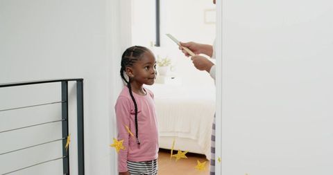 Young girl standing at doorway receiving item from parent in bright modern home