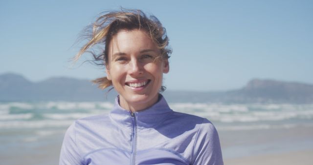Portrait of happy caucasian woman wearing sports clothes looking at camera and smiling at beach. Sport, healthy and active lifestyle.
