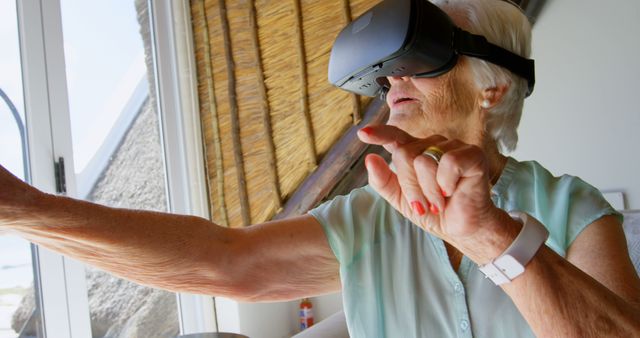 Senior woman engaging with a virtual reality headset, exploring interactive digital worlds. Perfect for illustrating the intersection of technology and aging. Ideal for use in articles about digital inclusivity for seniors, advancements in VR technology, or retirement home activities.