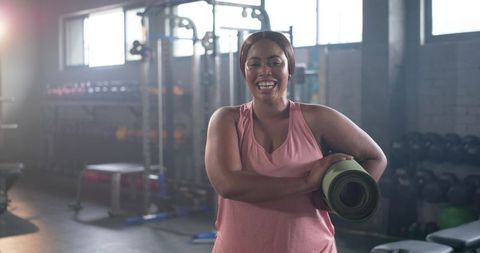 Smiling African American Woman Holding Yoga Mat in Gym Preparing for Workout