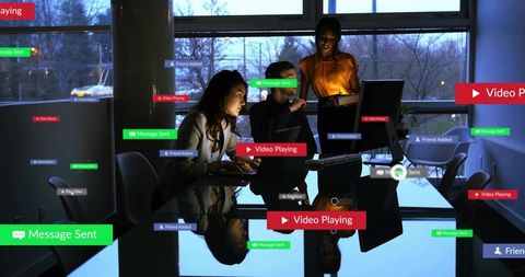 Business team collaborating around computer with social media alerts and video notifications