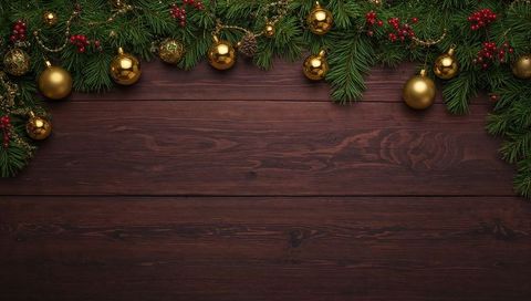 Hanging christmas garland with gold baubles and red berries on dark wood planks