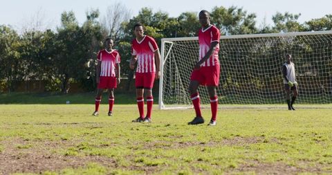 Soccer teammates lining up near goal on sunny day