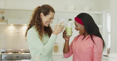 Diverse Friends Toasting Green Smoothies in Modern Kitchen