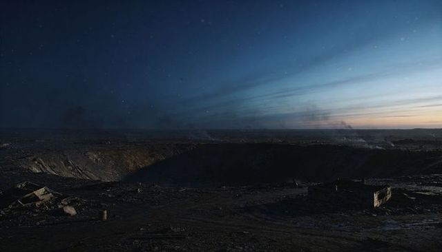 Massive impact crater casting deep shadows over deserted twilight wasteland with debris