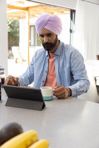 Indian Man with Tablet in Minimalistic Kitchen Setting