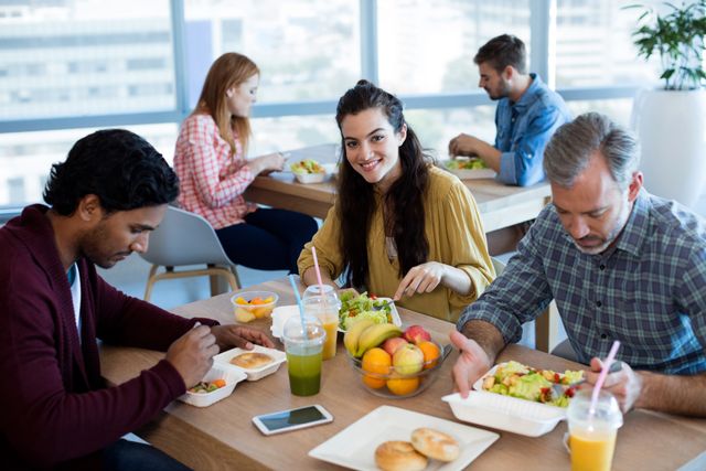 Business team enjoying a healthy lunch together in a modern office setting. Ideal for illustrating workplace culture, team bonding, and the importance of taking breaks. Suitable for articles on office life, teamwork, and employee wellness.