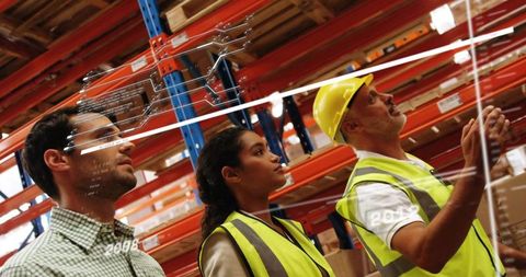 Warehouse leader guiding team reviewing digital plan overlay in pallet racking aisle