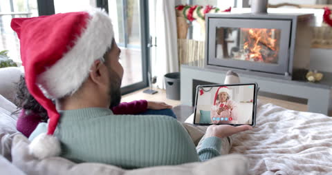 Festive Holiday Video Call with Family on Tablet by Fireplace