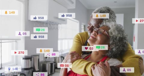 Elderly Couple Embracing Among Social Media Icons in Kitchen