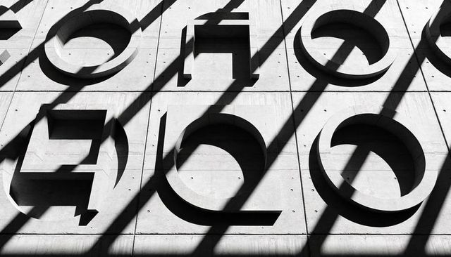Precast concrete facade with recessed circles and squares, diagonal shadow grid, pattern