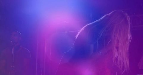 Female singer performing on hazy concert stage in atmospheric lighting