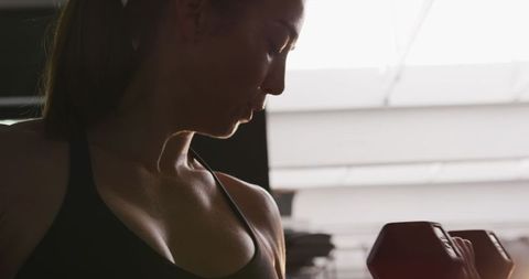Athletic woman focused on dumbbell workout in gym