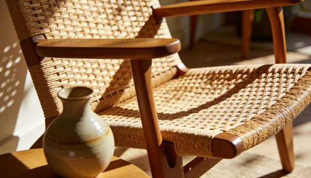 Sunlit handwoven-cord wooden lounge chair basking beside ceramic vase on small table