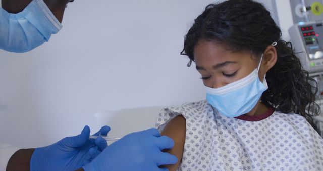 African american senior male doctor injecting covid-19 vaccine into a girl at hospital. vaccination for prevention of coronavirus outbreak concept