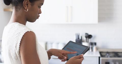 Woman analyzing smart home energy usage on tablet in modern kitchen
