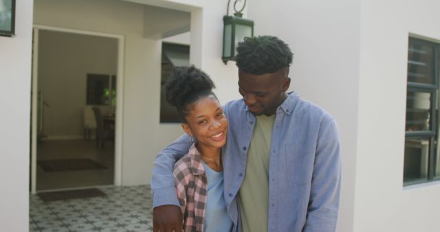 Image of happy african american couple embracing in front of new house. love, relationship, and starting new life together.