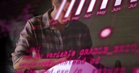Tech professional reviewing documents while analyzing projected neon code and analytics