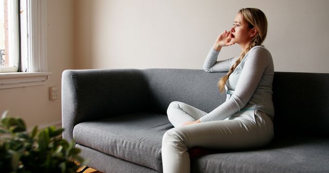 Contemplative Young Woman Sitting on Sofa in Modern Living Room - Download Free Stock Images Pikwizard.com